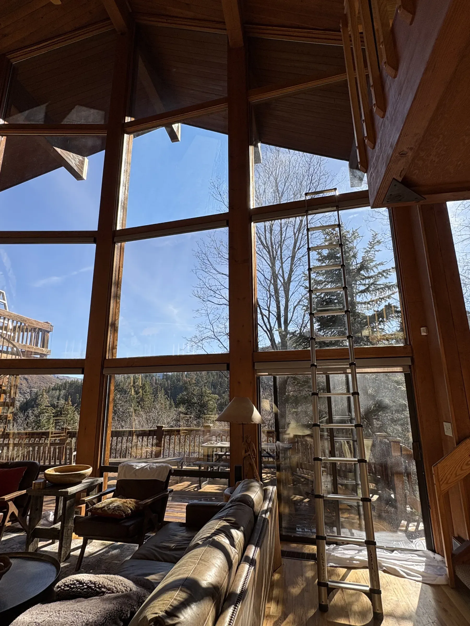 Sunlit wall of freshly cleaned cabin windows with a ladder set up for high glass